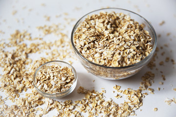 oat flakes in a transparent bowls on a white background