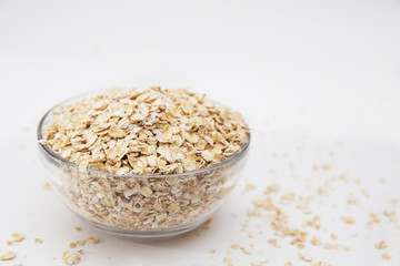 oat flakes in a transparent bowl on a white background