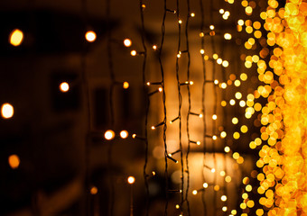 Festive dark blurred background with bokeh lights, electric garland and house