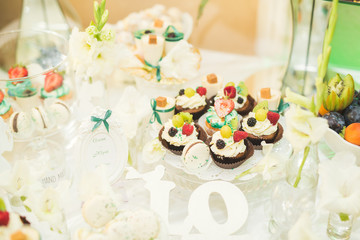 Delicious sweets on wedding candy buffet with desserts, cupcakes