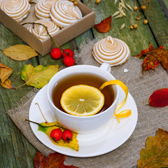 Tea with lemon on a wooden table. Table strewn with autumn leaves.