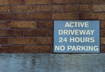 Active driveway 24 hours no parking sign on a building