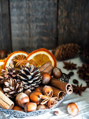 Fototapeta na wymiar Winter ingredients nuts, cones, oranges, cinnamon star anise in a bowl. Rustic style