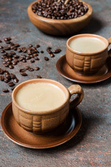 Coffee espresso in small brown clay cups and coffee fried grains on a dark background with copy space