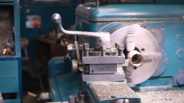 Close up of bronze bushing making on old shabby blue lathe, metal shavings flying. Shot with Sony a7s and Atomos Ninja Flame in shabby car service