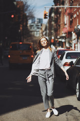 Fototapeta premium Woman in grey suit poses on the street of New York in a windy day