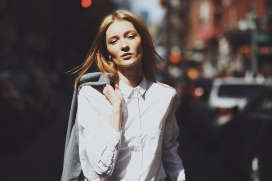 Girl holds her jacket on the shoulder posing on the street