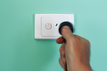 Hand removing a power cable from an electricity wall outlet to illustrate the concept of...