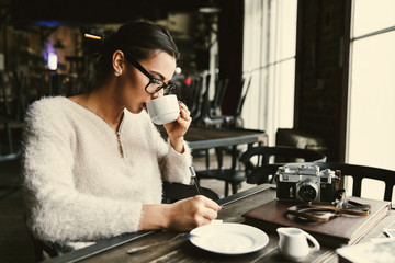 Thoughtful lady makes some notes while she sits with a cup of coffee in cafe