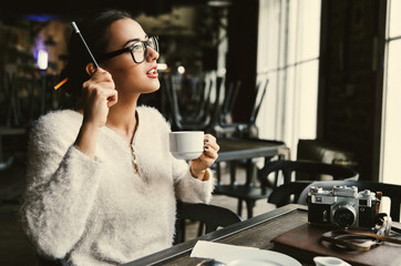Thoughtful lady makes some notes while she sits with a cup of coffee in cafe