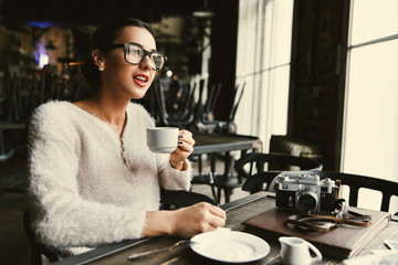 Thoughtful lady makes some notes while she sits with a cup of coffee in cafe