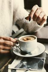 Woman drops sugar in a cup of coffee