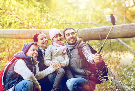 happy family with smartphone selfie stick in woods