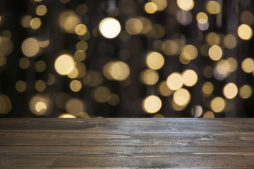 Blurred gold garland and wooden tabletop as foreground. Image for display or montage your christmas...