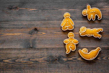 Gingerbread cookies in shape of yoga asanas on dark wooden background top view copyspace