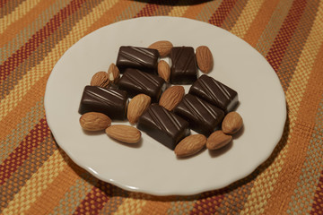 Chocolate and Almonds on a white dish. Color Background