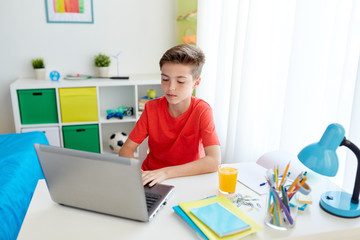 student boy typing on laptop computer at home