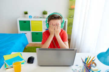 boy in headphones playing video game on laptop