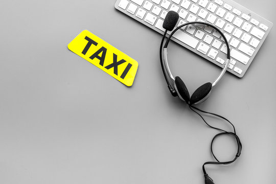 Call taxi online. Taxi label, keyboard, headphones on grey background top view copyspace