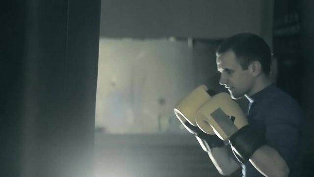 The athlete trains before the fight. A boxer punches the heavy bag. Black background