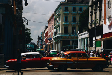 Old retro cars painted in bright colors ride along the street somewhere on Cuba