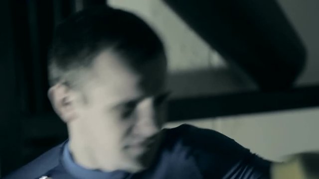 The athlete trains before the fight. A boxer punches the heavy bag. Black background