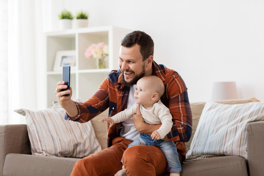 happy father with baby boy taking selfie at home