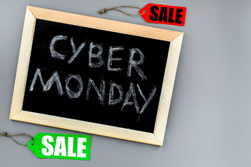 Words cyber monday written on blackboard and sale labels on grey background top view