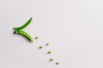 Open green pea pod and seeds on white background. Top view, copy space.