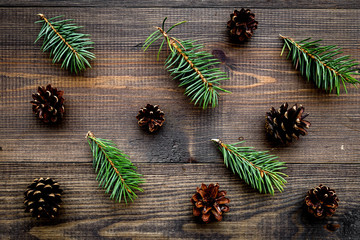 Spruce branch and pinecone pattern on wooden background top view