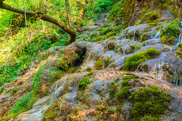 Little flows of waterfall in the park Berendeyevo Tsarstvo in sunny summer day, Sochi, Russia