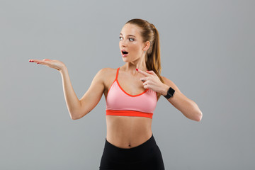 Fototapeta na wymiar Shocked young sports woman pointing to copyspace.