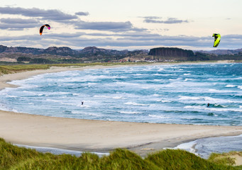 Kitesurfing men in action on stormy sunset evening at Brusand Beach, Norway.