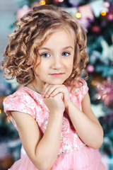 Obraz na płótnie Canvas portrait of a little blonde girl with curls near a Christmas tree
