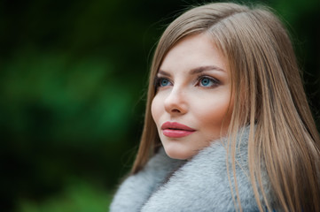 Fototapeta premium Beautiful young blonde woman wearing fur autumn coat