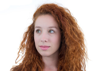 Young woman looks to the side. She's interested in something. She is redheaded and young. White background. Black shirt..