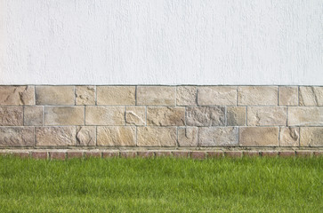 Rich white wall, horizontal rectangular stones and a green lawn for the background