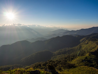 The bright sunrise of morning sky is shining through the white fluffy cloud, creates shadow and shade to the green mountain range. This great nature can be seen after trekking for 1 day at Doi Phu Wae