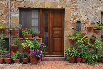 Fototapeta na wymiar old wooden door decorated with flower pots from the medieval town, Tuscany, Italy