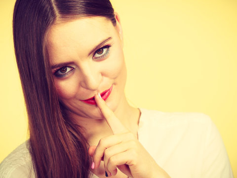 Mysterious woman showing silence gesture with finger