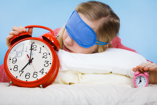Sleeping woman wearing pajamas holding clock