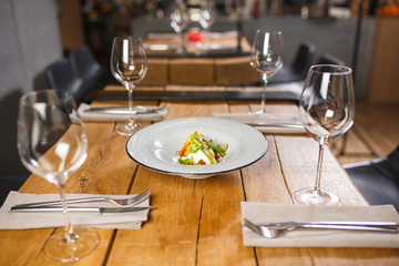 A wooden table in the restaurant, served with glasses in the middle, is a dish with Vegetarian salad mozzarella cheese and vegetables