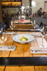 A wooden table in the restaurant, served with glasses in the middle, is a dish with Vegetarian salad mozzarella cheese and vegetables