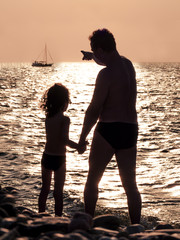 Father with her son on the beach. Sunset