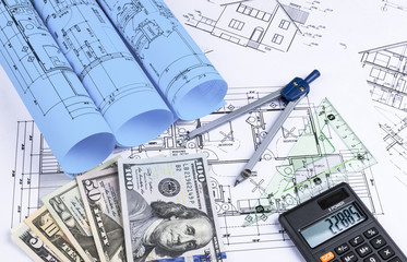 A blueprint of an architect with money, calculator. symbolic photo for financing and planning of a new house. Blueprints rolls and a drawing instruments on the worktable