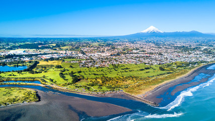Aerial view on Taranaki coastline with a small river and New Plymouth and Mount Taranaki on the background. Taranaki region, New Zealand