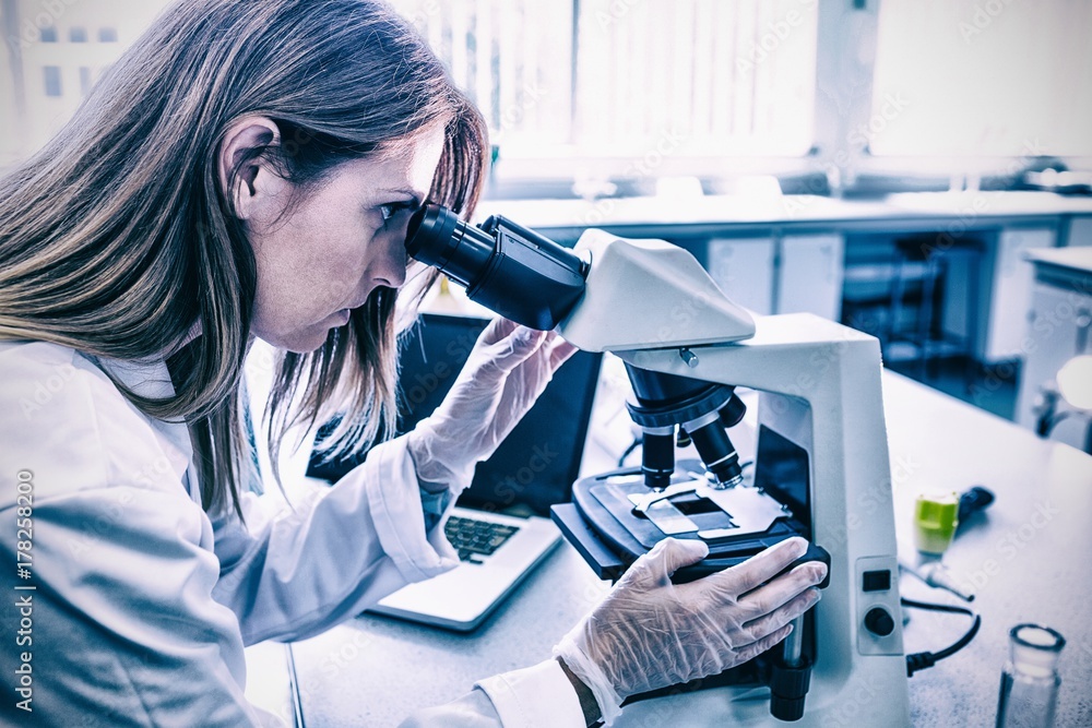 Poster scientist working with a microscope in laboratory