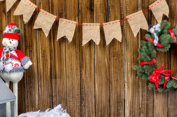 Happy New Year card with a snowman and wreath on a wooden background. Copy space.