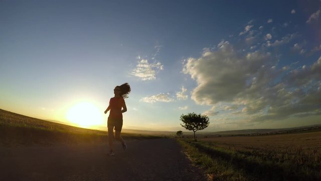 Running at sunset. Young woman exercising in summer afternoon. Slow motion.