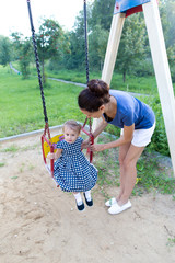 The girl and her mother on the Playground. Swing